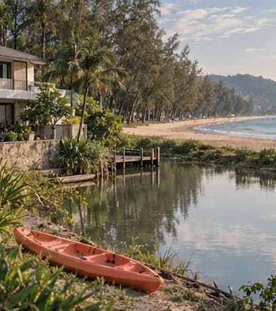 A long straight beach with casuarina pines and a lagoon canal with a villa, calm sea